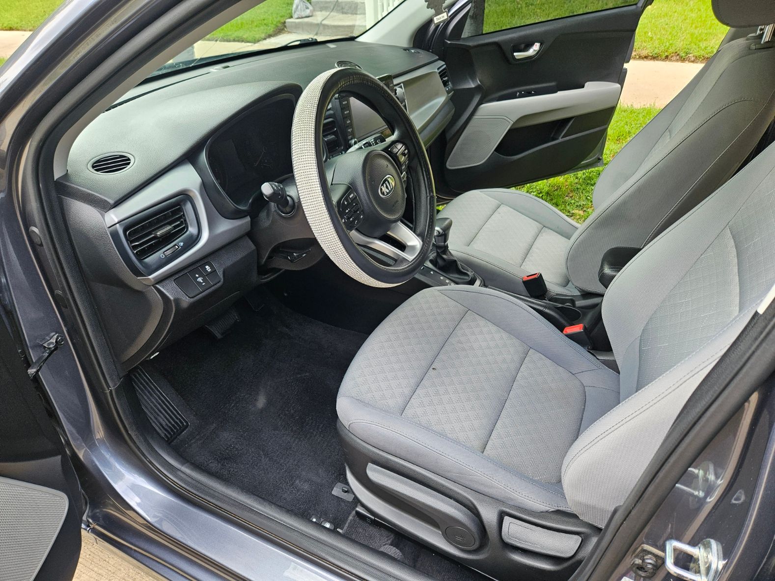 The inside of a car with the door open and the steering wheel visible.