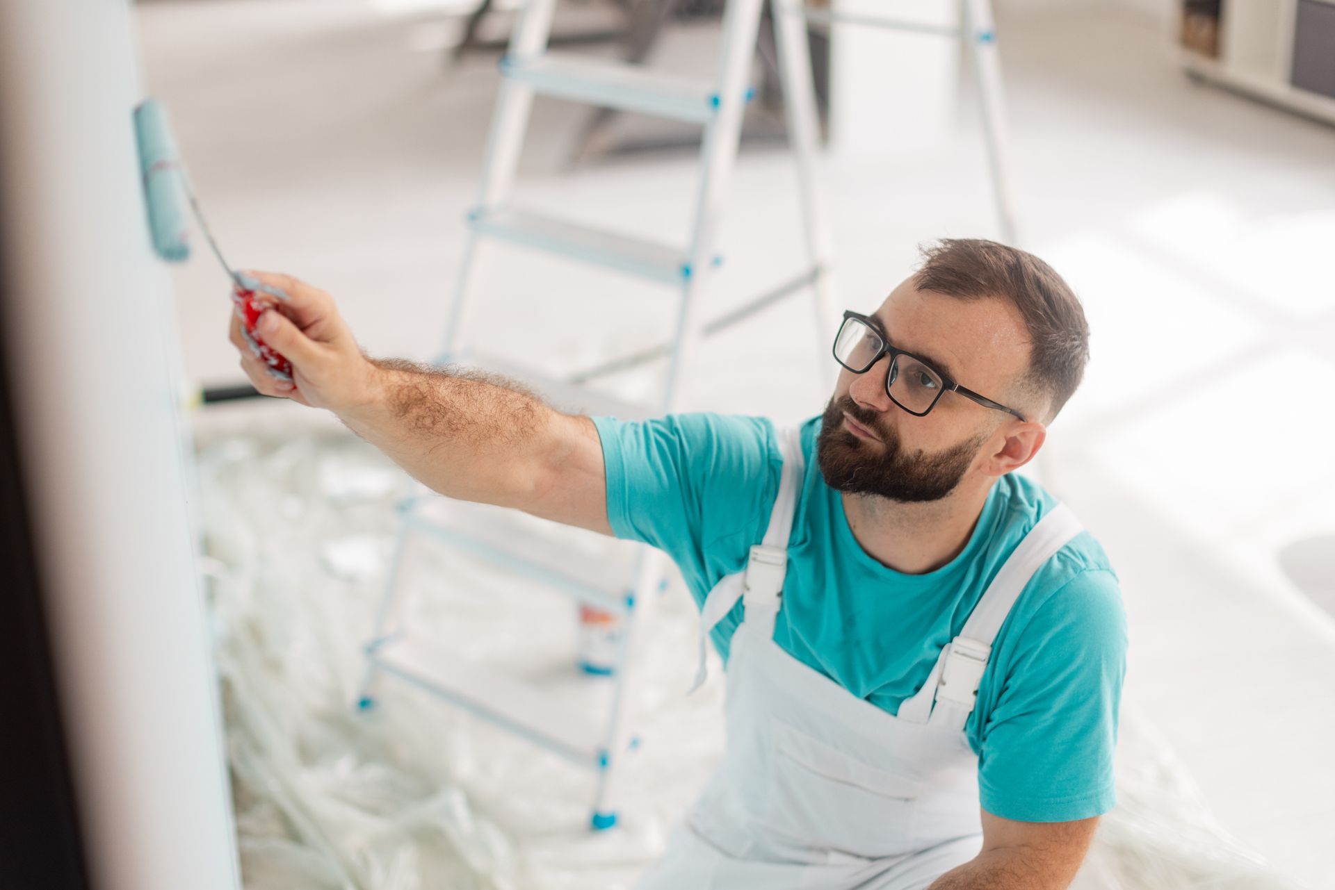 Residential painters applying light blue paint to indoor column in bright, modern living space.