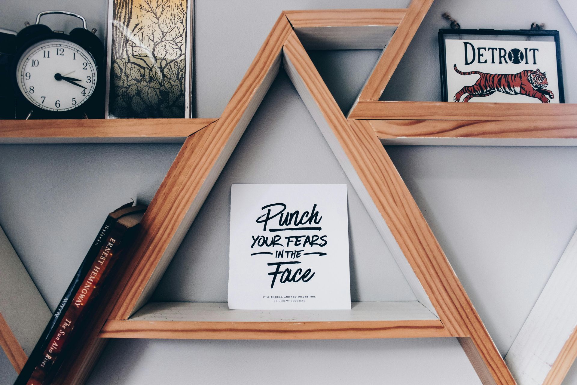 Wooden geometric shelves with decorative items, including a clock and artwork. 