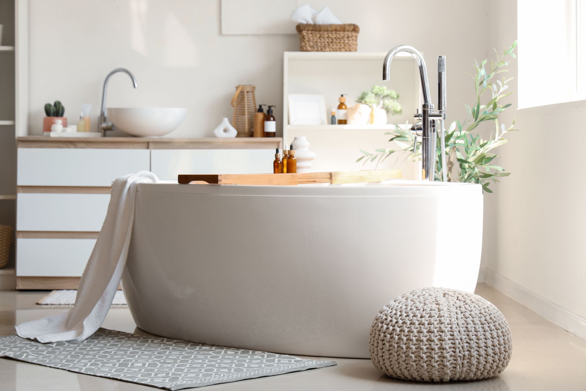 Bright bathroom with a freestanding tub, towel draped over it, and plants on a shelf by the window.
