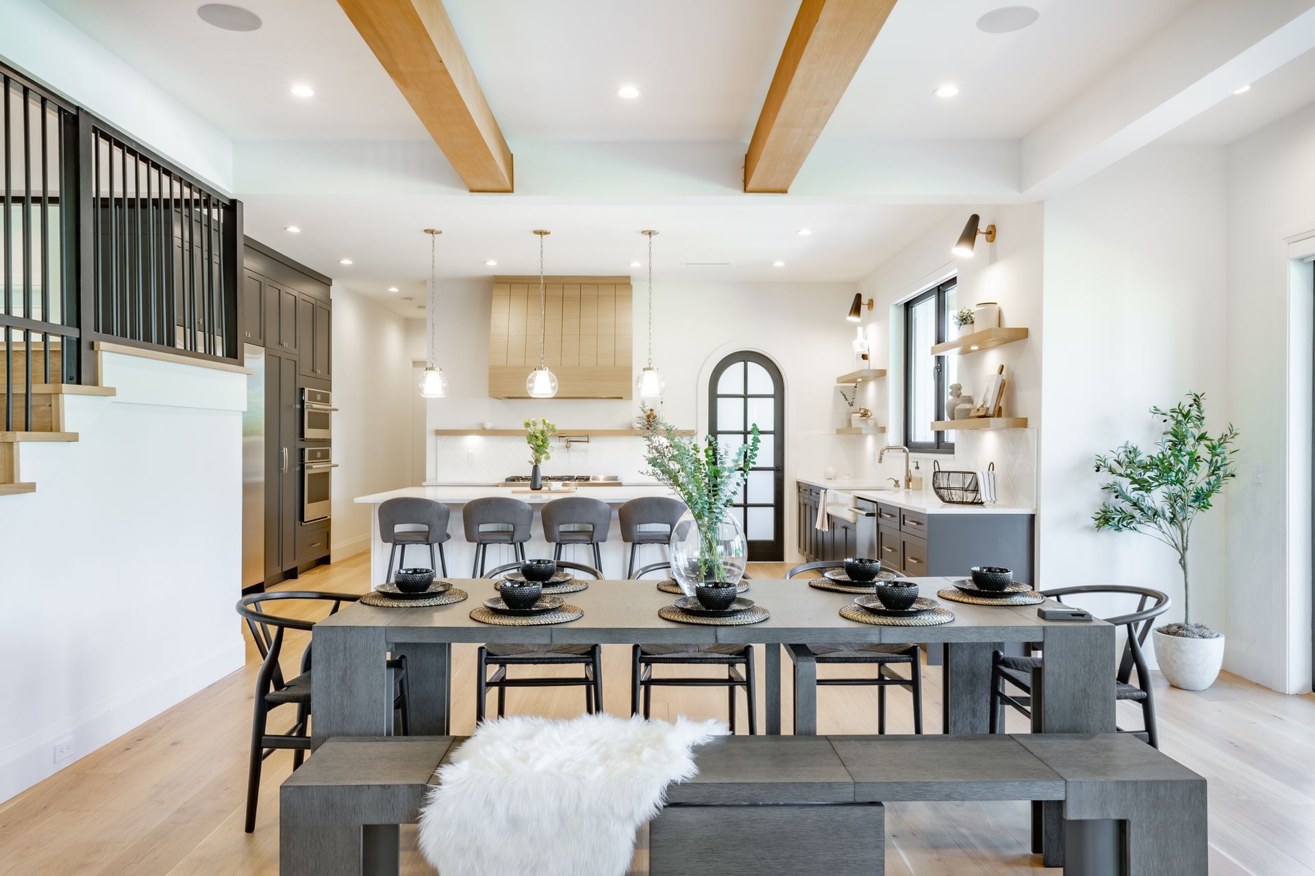 Spacious modern kitchen and dining area with gray table, black chairs, and wooden beams.