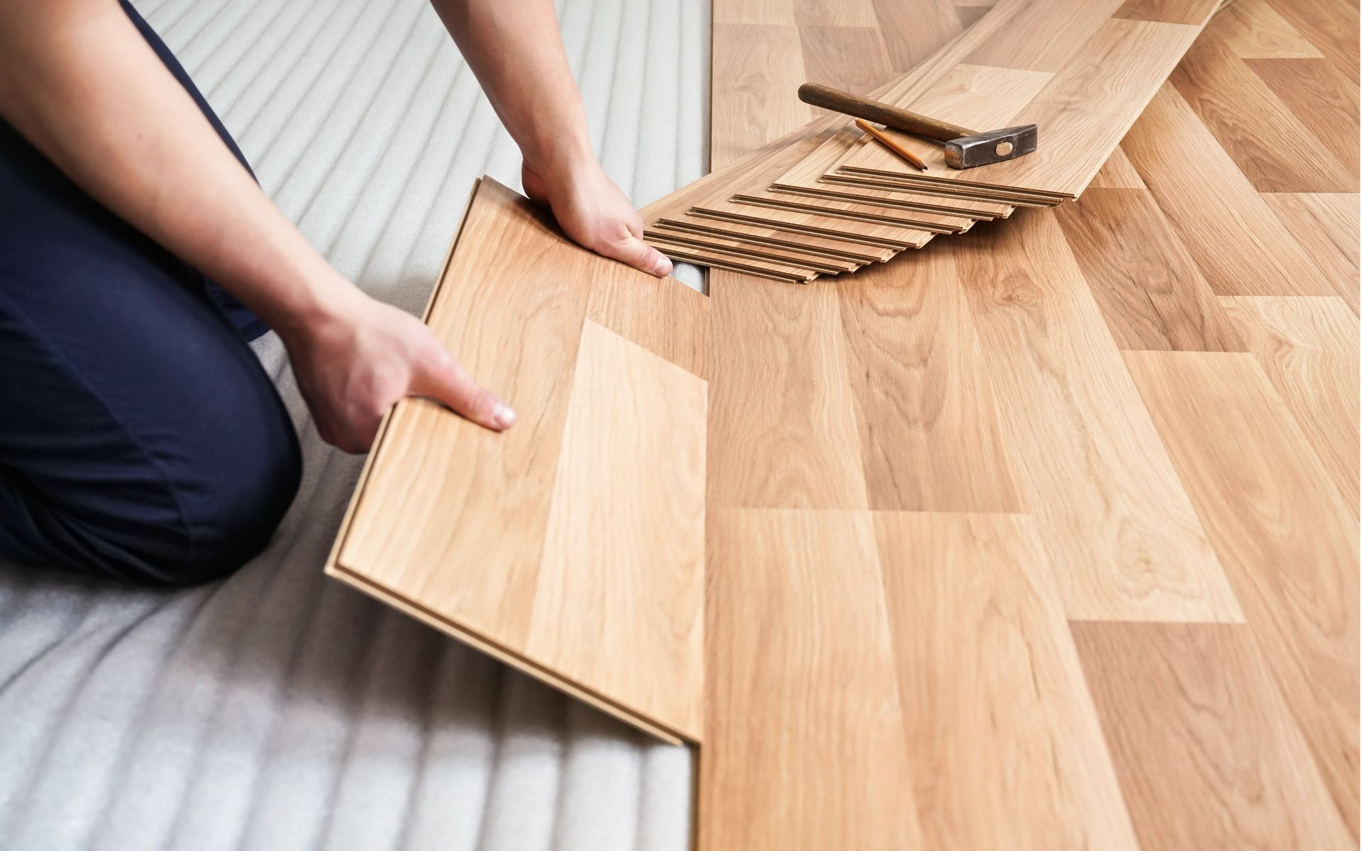 the construction worker is laying laminate flooring