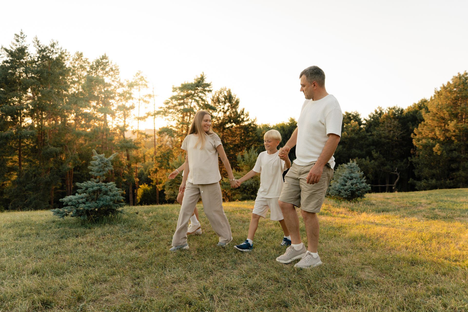 Three people walking on grass at sunset in a park