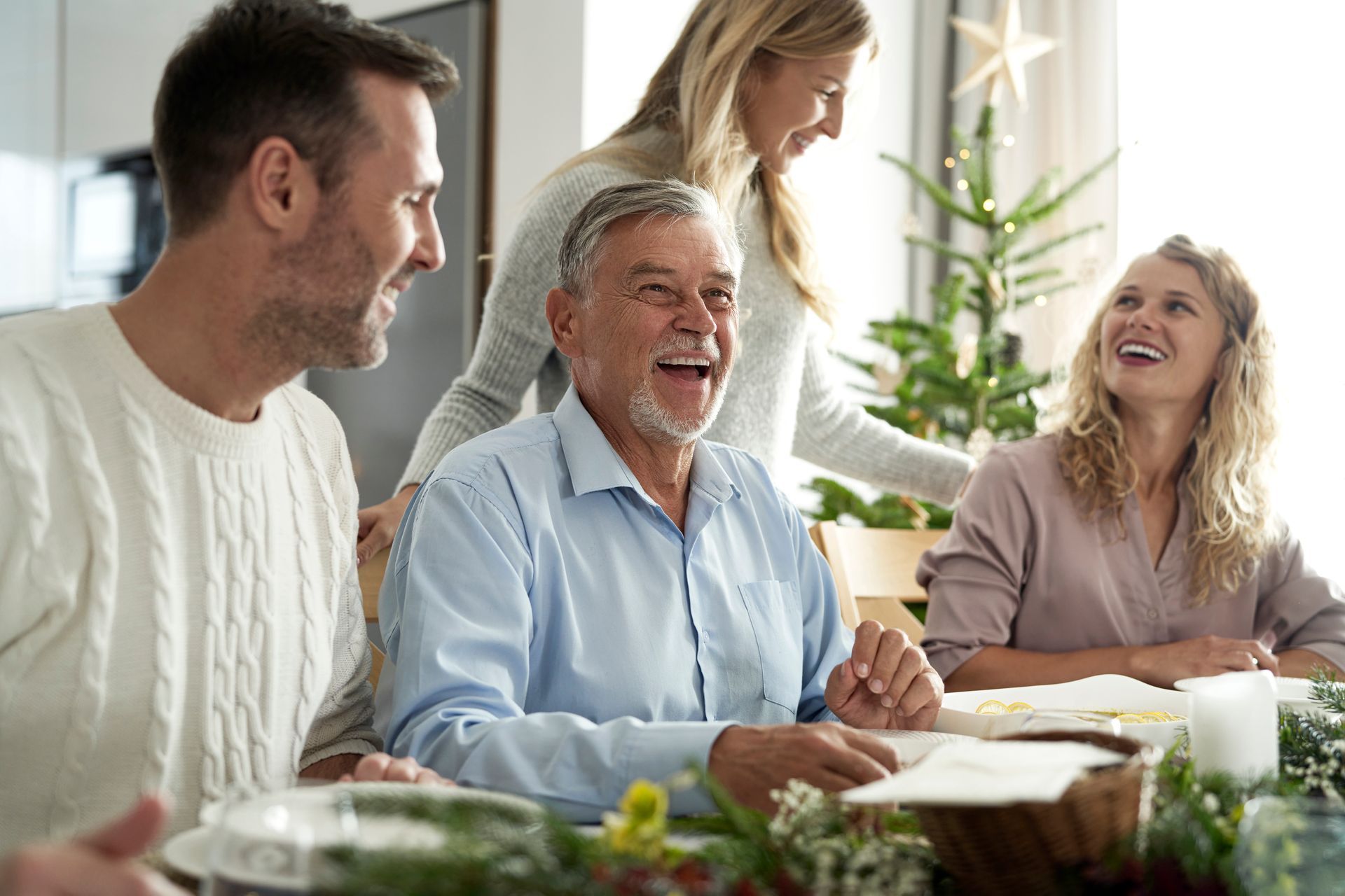 Family gathered around a dining table, smiling and sharing a meal in a bright kitchen.