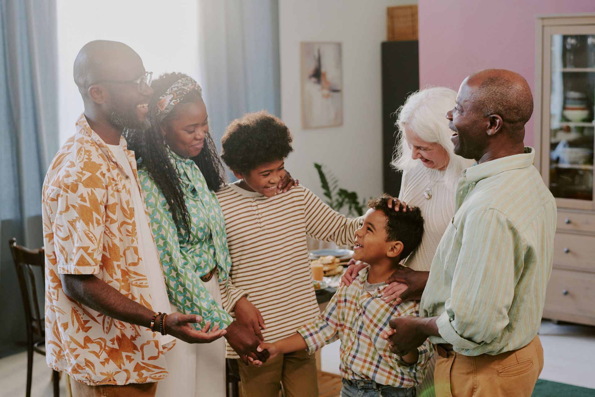 Five people smiling and holding hands in a bright living room