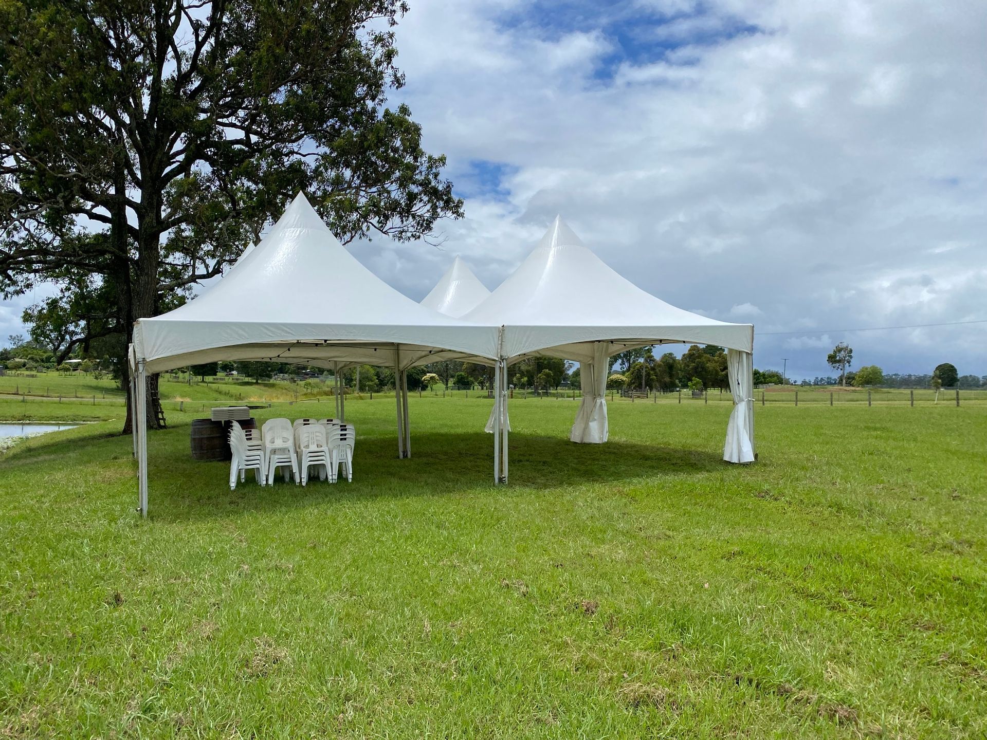 A White Tent Is Sitting In The Middle Of A Grassy Field — Red Shed Hire In Wauchope, NSW