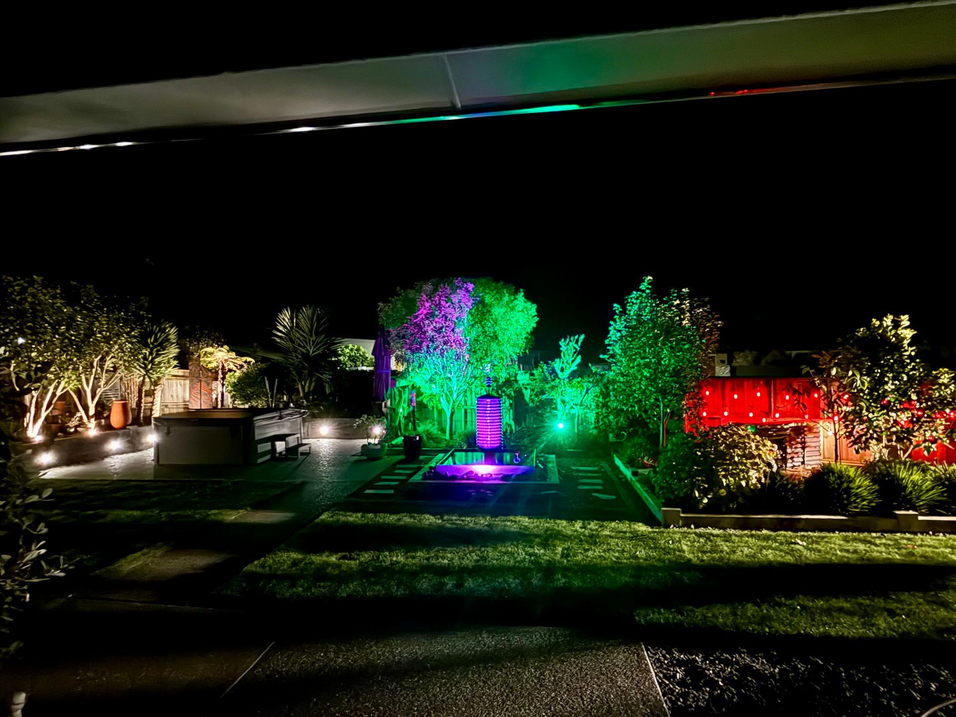 Modern patio with dining table, steps to sliding doors, lush greenery, and sunset sky