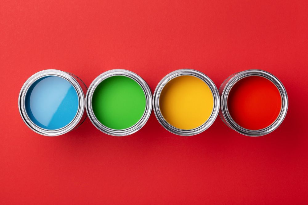 Row of Cans of Colourful Paint on Red Background — Paint & Decor in Pioneer, QLD