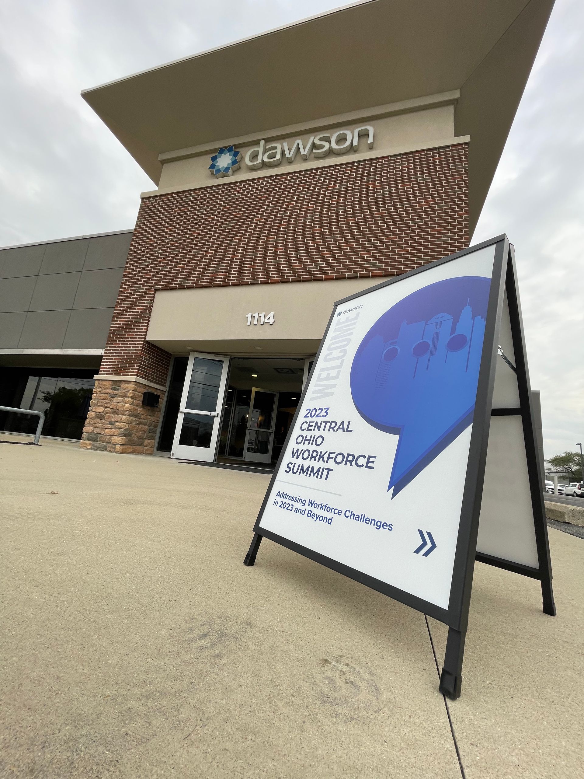 A sign for Dawson Workforce Center stands on a sidewalk outside the building entrance.