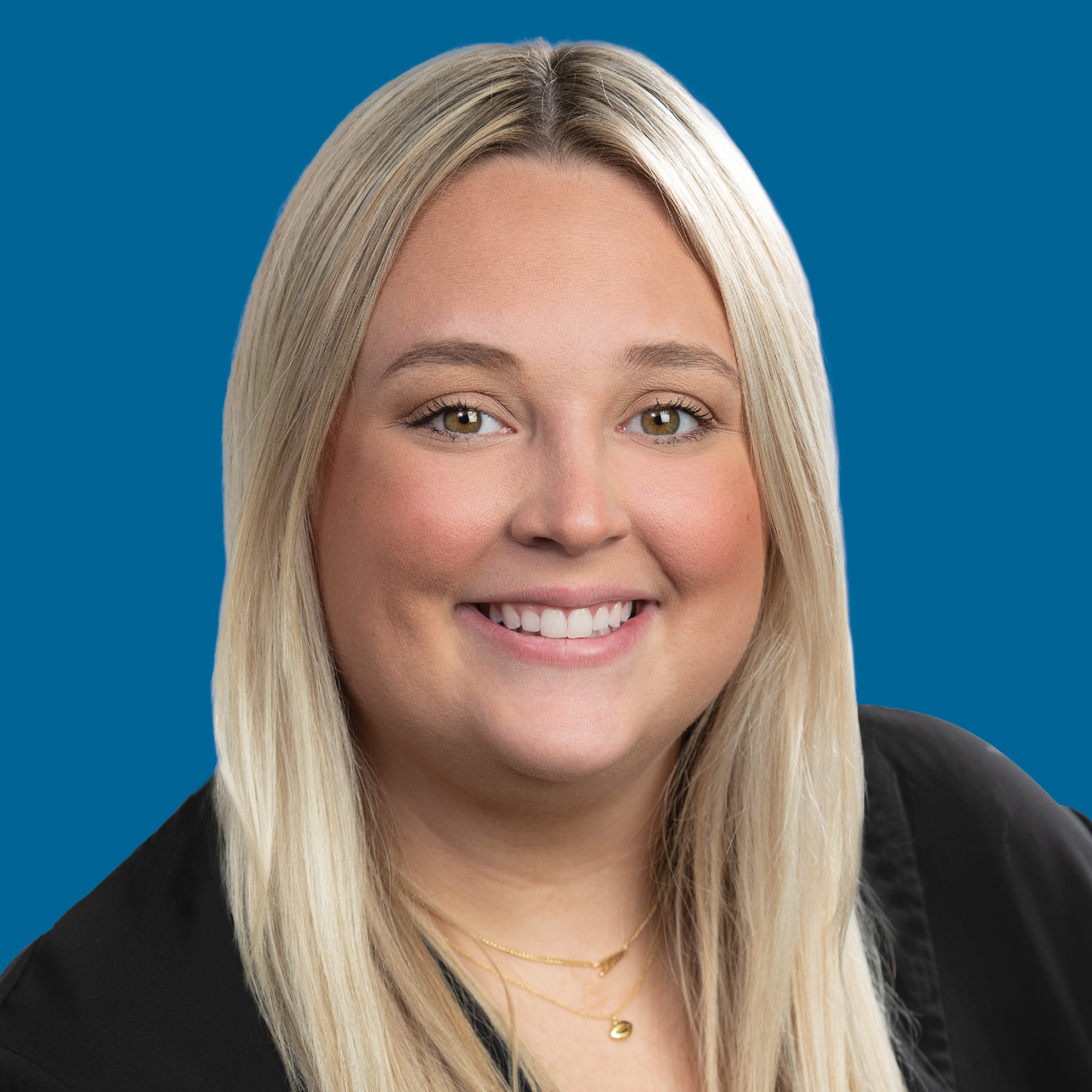 A smiling person with blonde hair against a solid blue background.