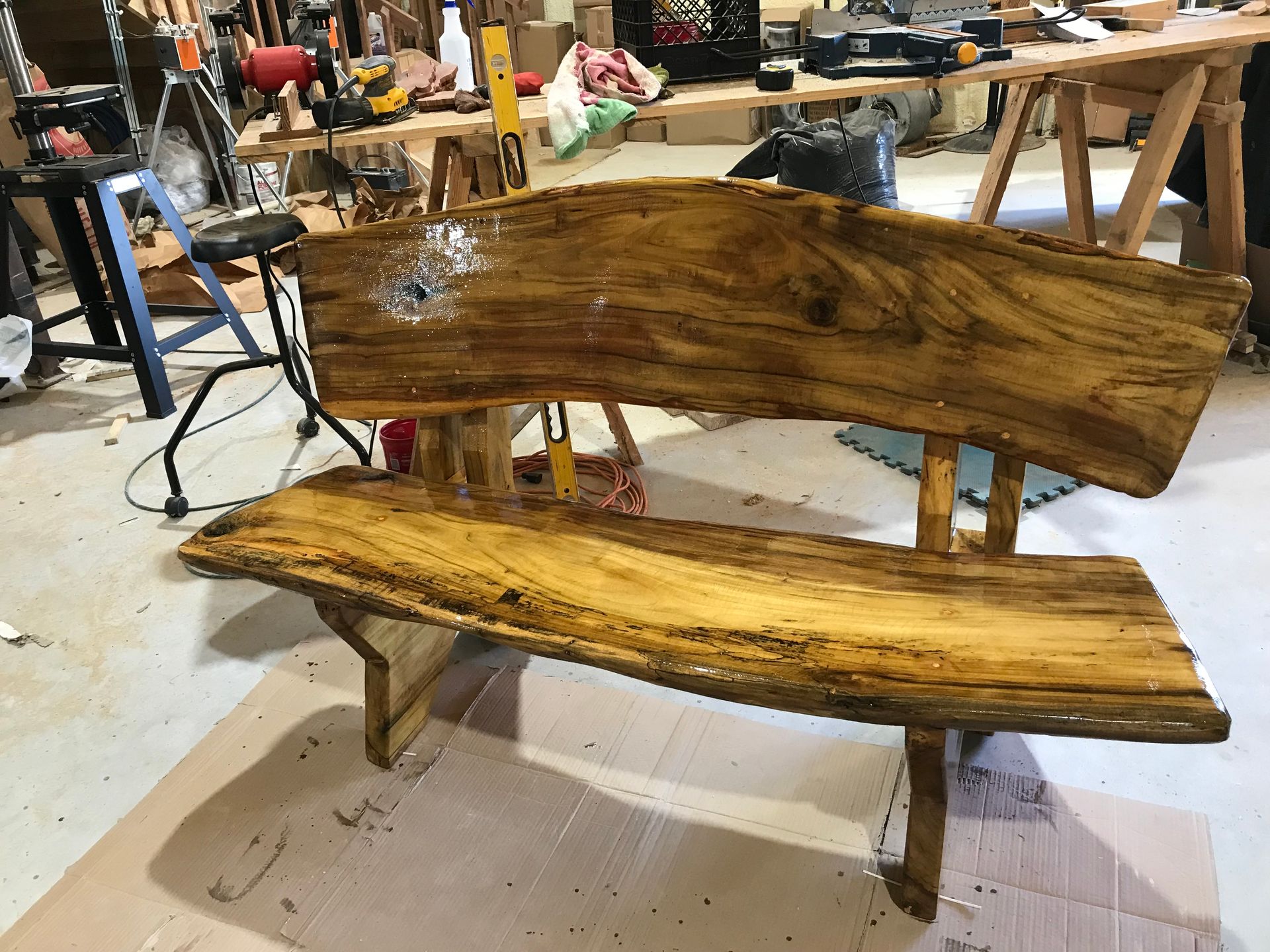 Rustic wooden bench with curved seat and back in a workshop.