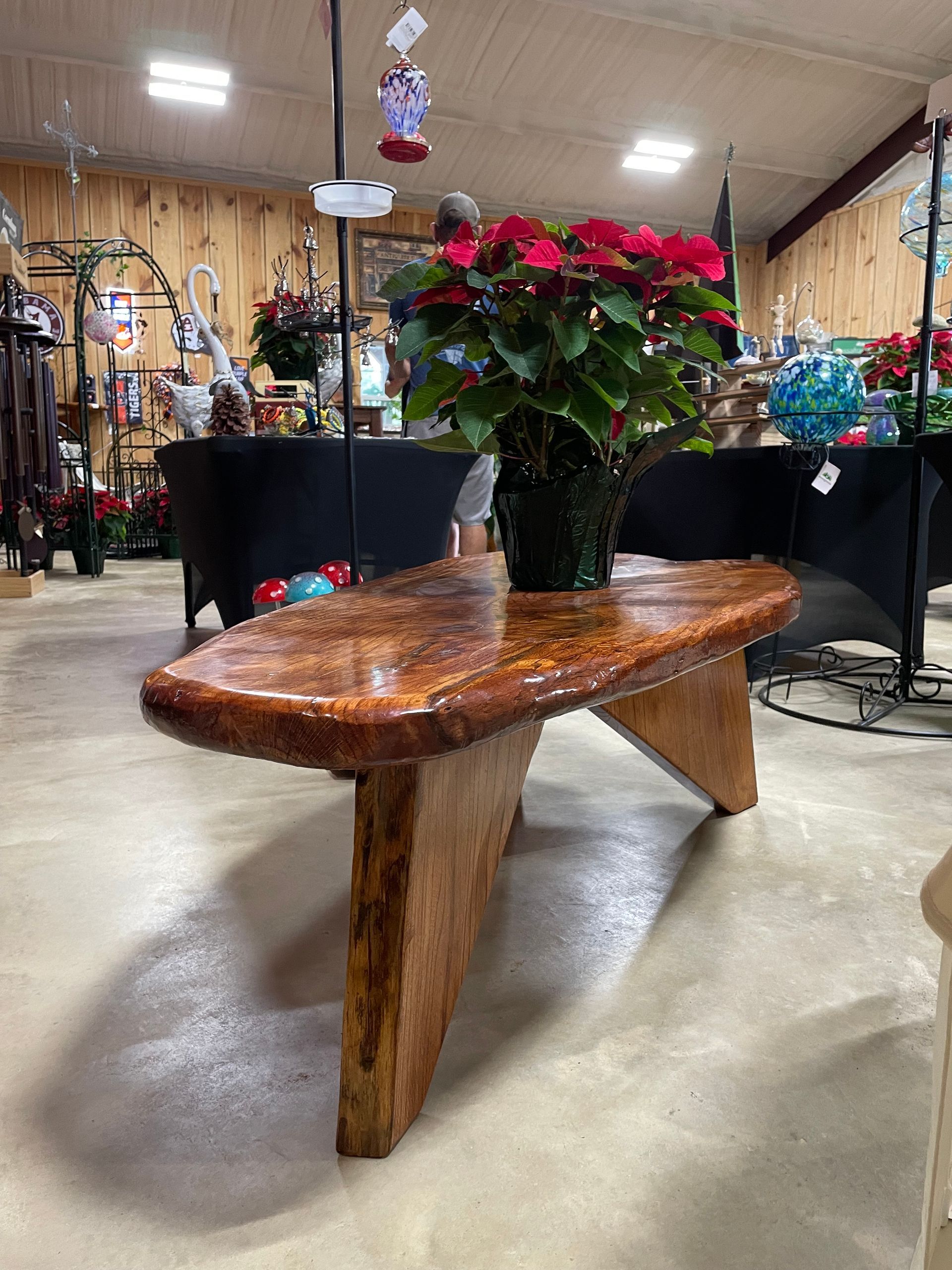 Wooden coffee table with a poinsettia plant in a retail store.