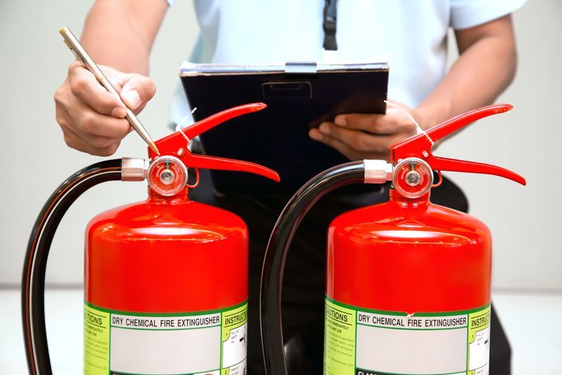 Man Inspecting Two Fire Extinguisher— Fire Safety in Tamworth, NSW