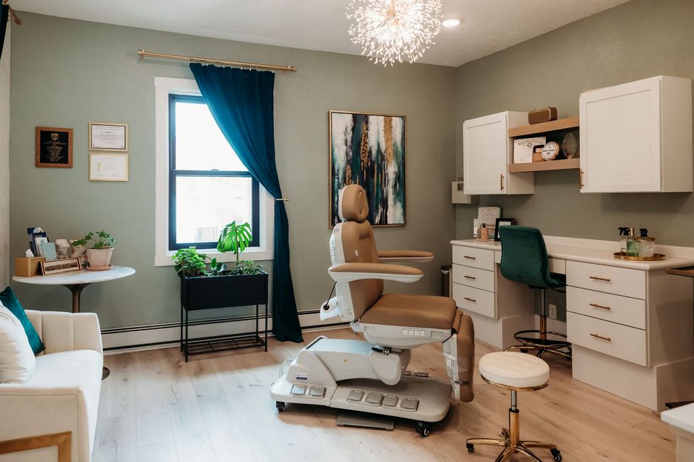 Modern dental exam room with chair, desk, cabinets, and blue curtains