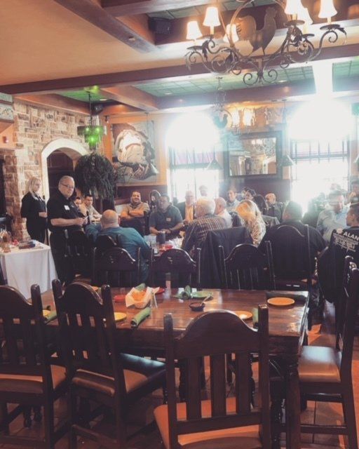 Cozy restaurant interior with diners seated at tables under warm chandeliers and bright windows