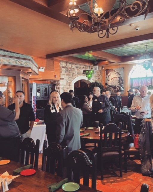 People chatting in a warmly lit restaurant with rustic decor and wooden chairs.