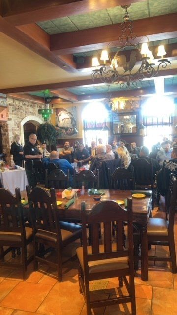 Dimly lit restaurant with diners seated at tables under chandeliers and wooden beams.