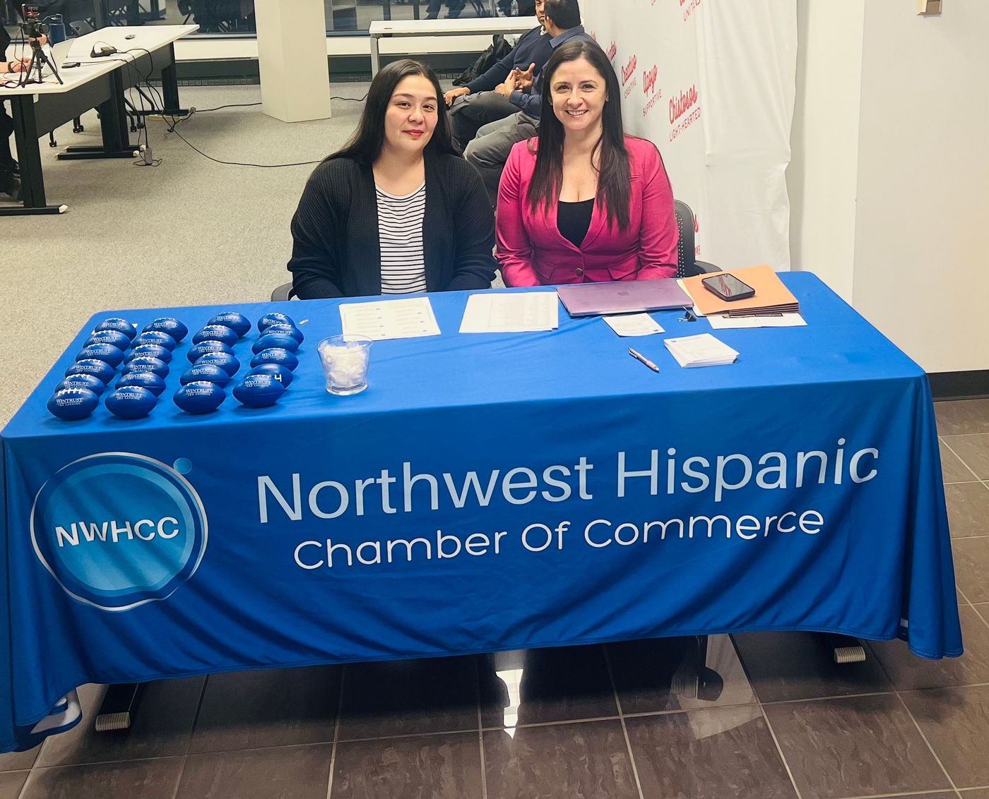 Northwest Hispanic Chamber of Commerce booth with two women behind a blue tablecloth and display items