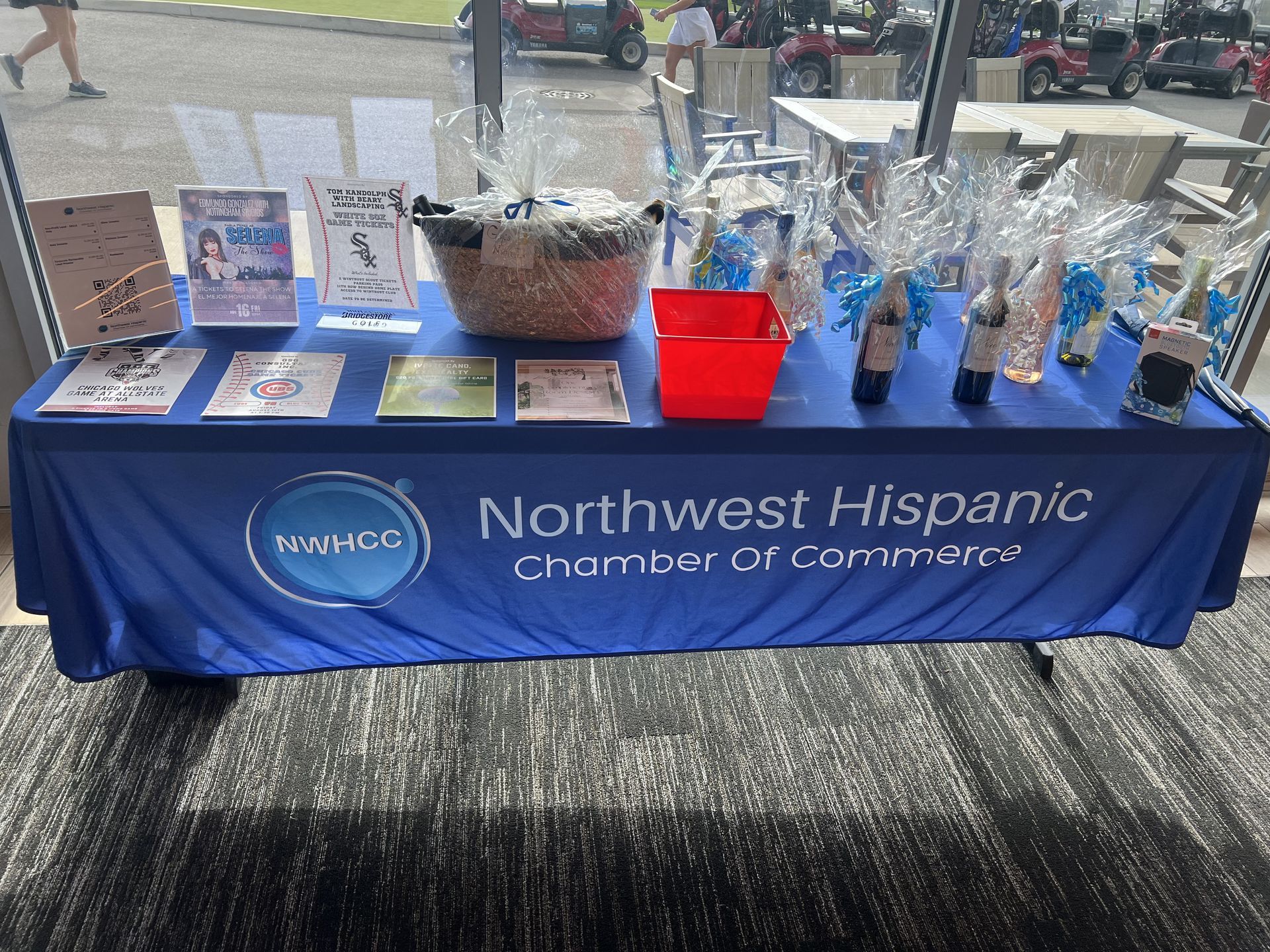 Northwest Hispanic Chamber of Commerce booth with blue tablecloth, flyers, gift bags, and display items