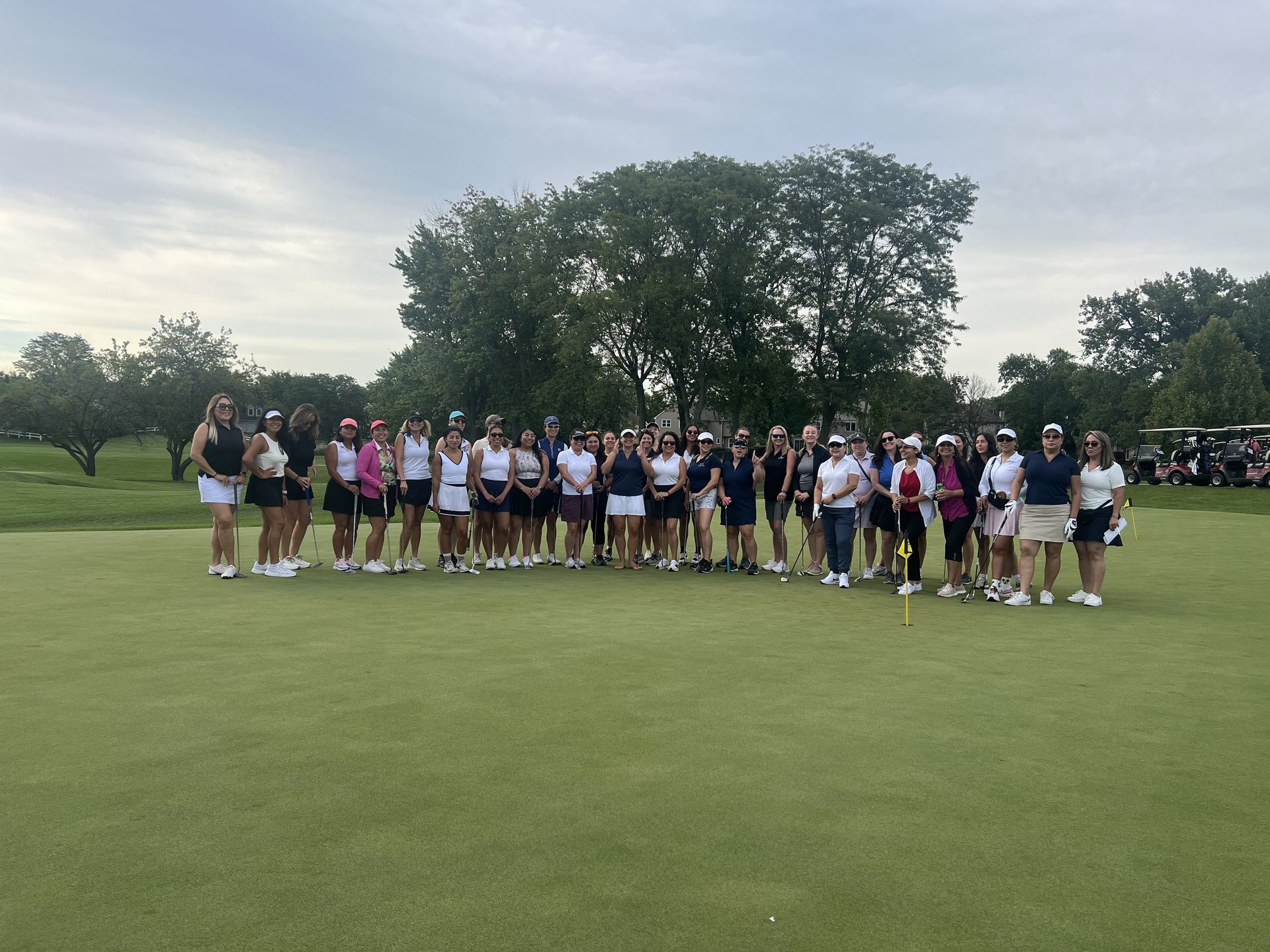 Group of athletes standing on a golf course fairway with trees in the background