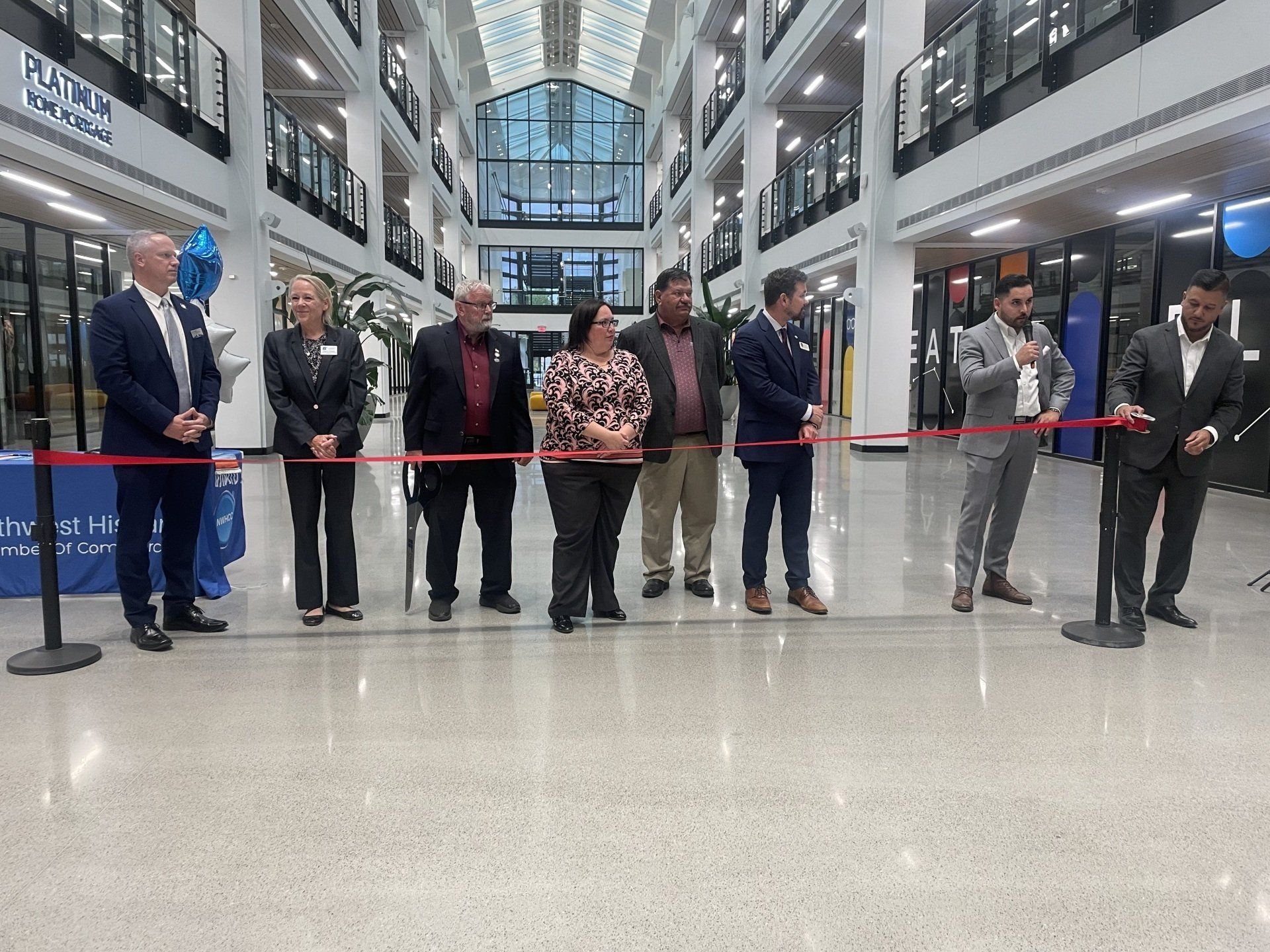 Ribbon-cutting ceremony with a row of people in a bright indoor atrium