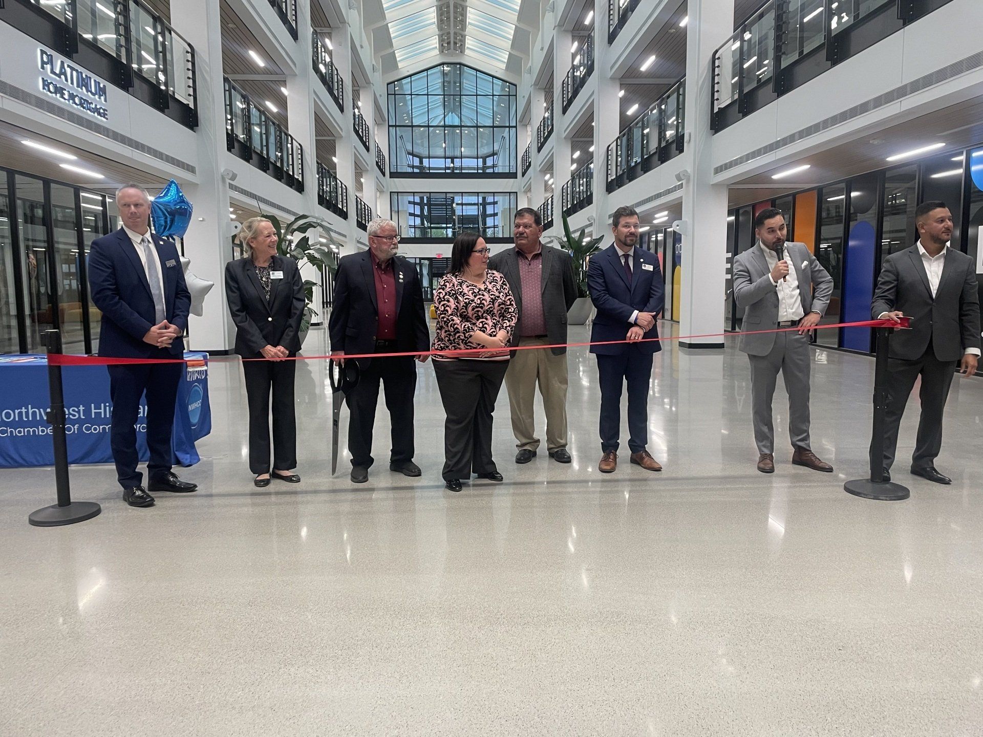 Ribbon-cutting ceremony in a bright atrium with officials standing behind a red ribbon