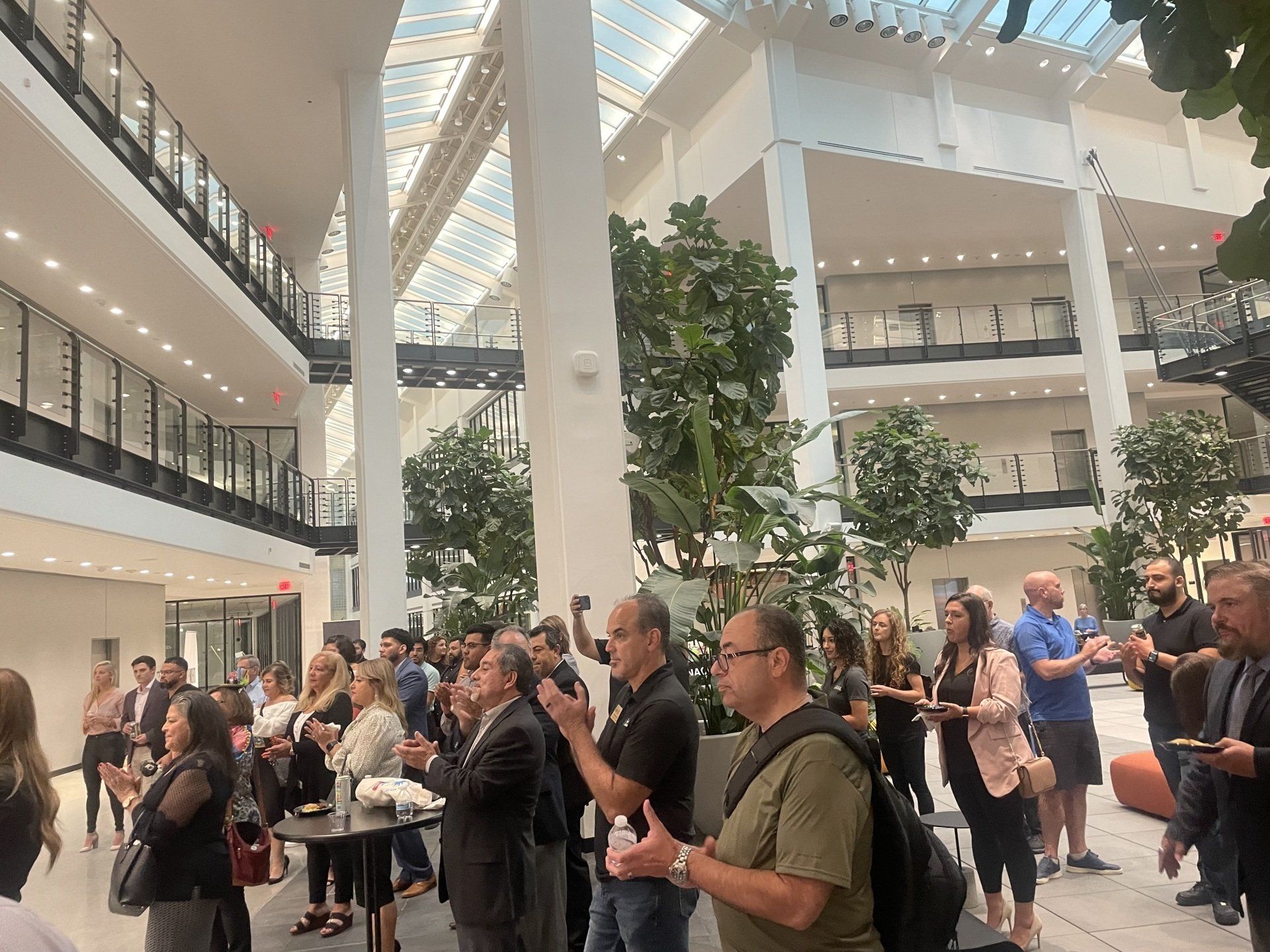 Crowded atrium with people mingling under bright skylights and upper balconies