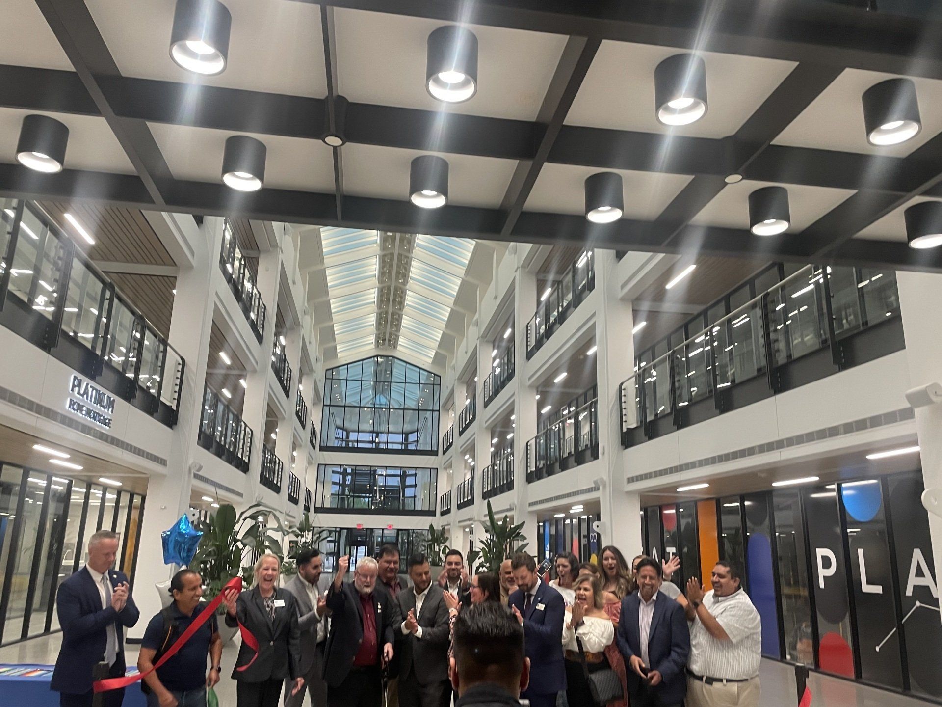 Group posing in a bright indoor mall atrium with glass railings and hanging lights