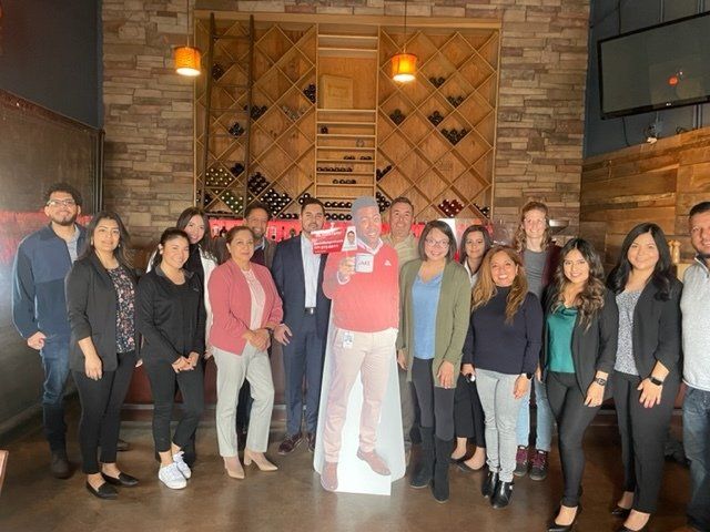 Group of people posing indoors in a rustic restaurant, with one man in red centered in front.