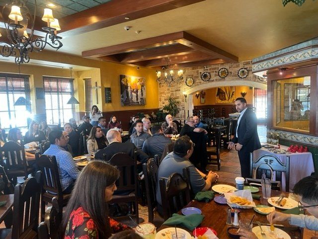 People dining in a warmly lit restaurant with wooden beams and large windows.