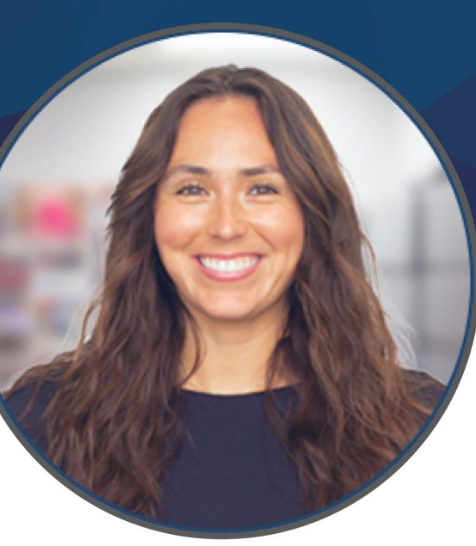 Smiling woman with long brown hair in a navy top against a blurred office background