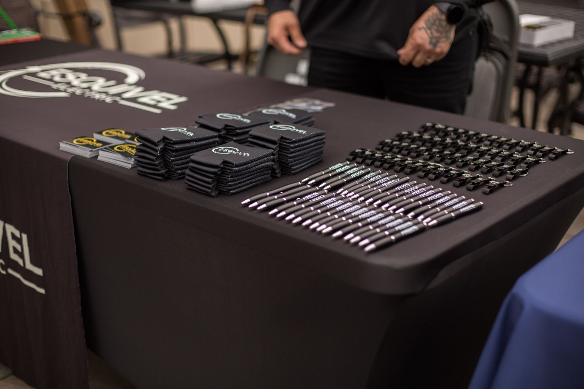 Black table with neatly stacked pens and badges at a promotional booth