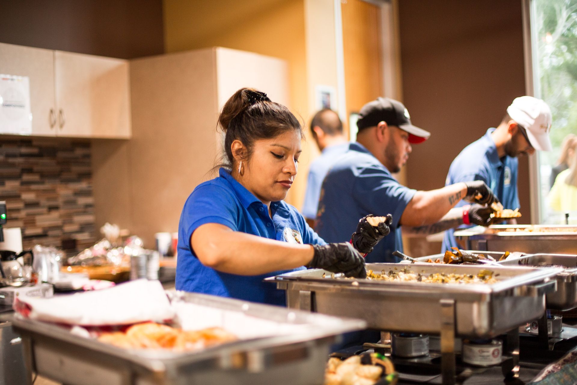 Chefs in blue uniforms plating food in a busy kitchen line
