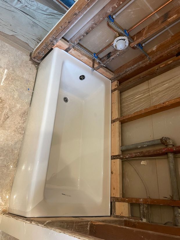 A bathtub is being built into a wall in a bathroom.