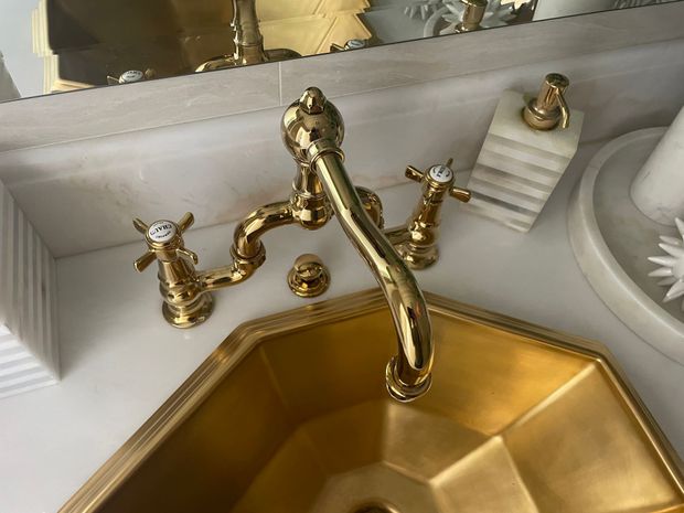 A bathroom sink with a gold faucet and white handles