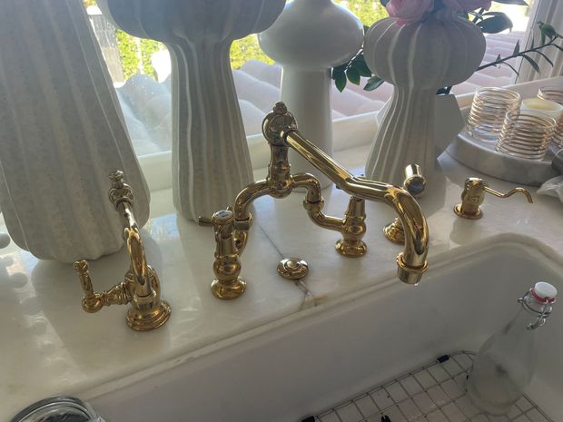 A sink with gold faucets and vases on the counter