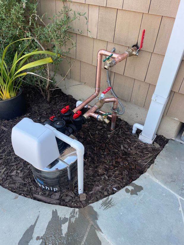 A hose is sitting in the dirt next to a brick wall.