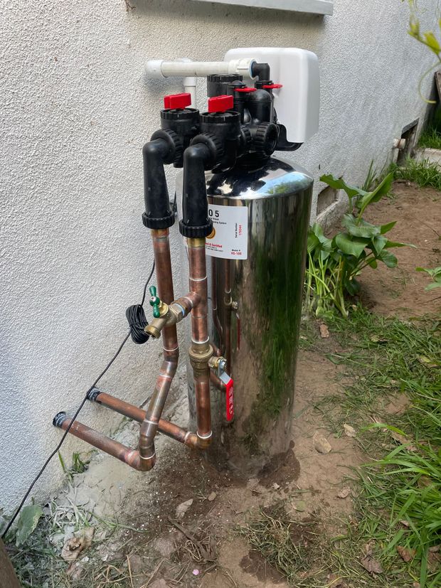 A stainless steel water filter with copper pipes attached to it.