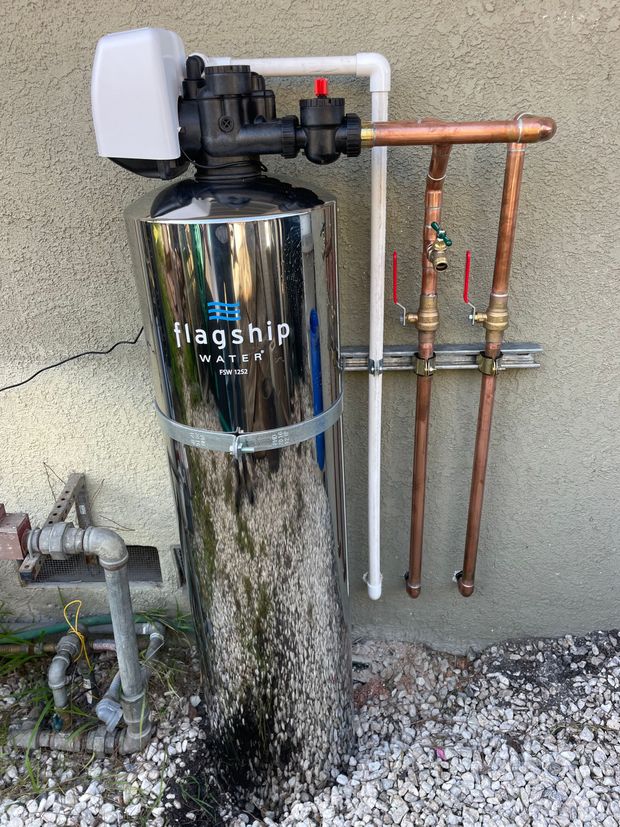A stainless steel water filter is attached to a wall.