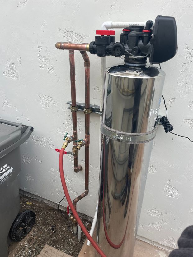 A stainless steel water filter with copper pipes attached to it.