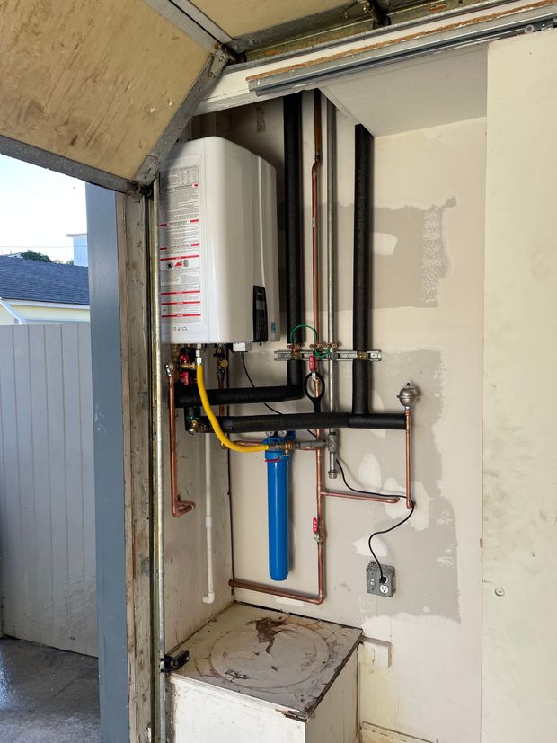 A water heater is installed in a garage next to a door.
