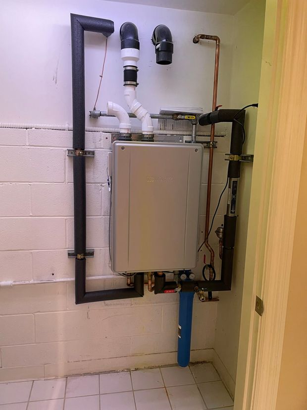 A bathroom with a boiler and pipes on the wall