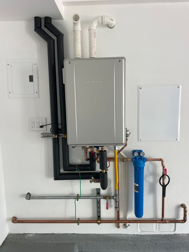 A water heater is attached to a wall with pipes