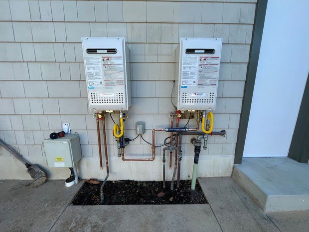Two water heaters are attached to the side of a building