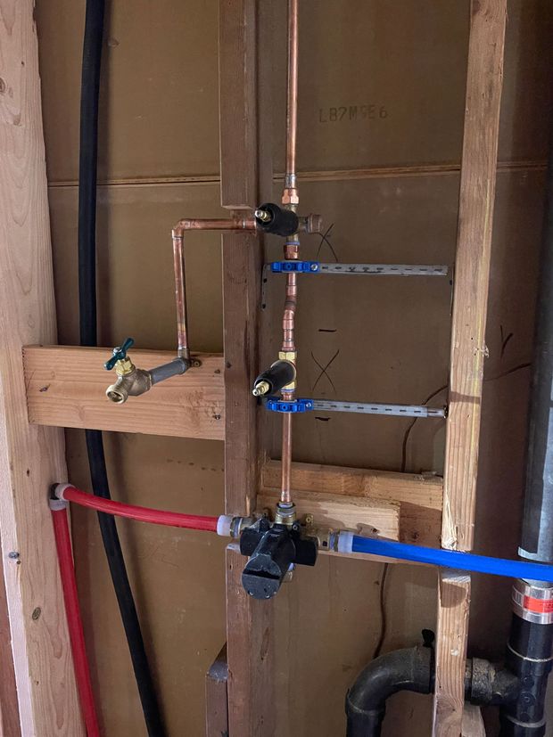 A close up of a bathroom plumbing system in a wooden frame.