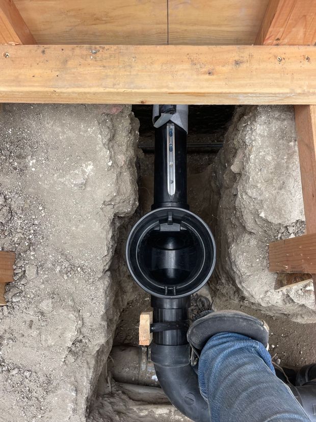 A person is working on a pipe in a hole in the ground.