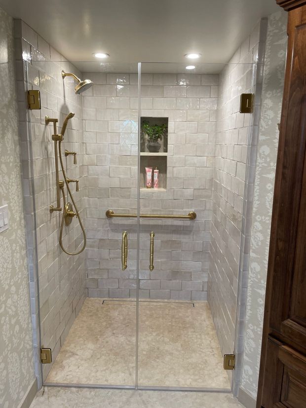 A bathroom with a walk in shower with a glass door.