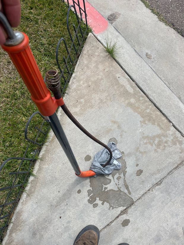 A person is holding a soldering iron on a sidewalk.