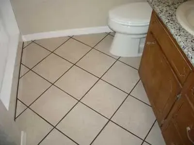 A bathroom with a toilet , sink , and tile floor.