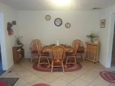 A dining room with a table and chairs and a clock on the wall.